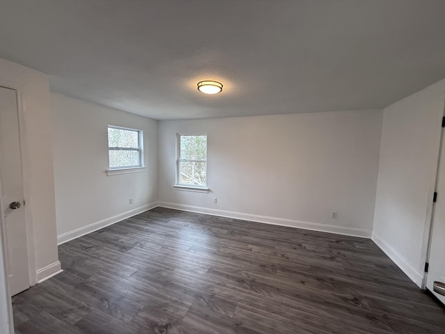 empty room with dark hardwood / wood-style flooring and a baseboard radiator