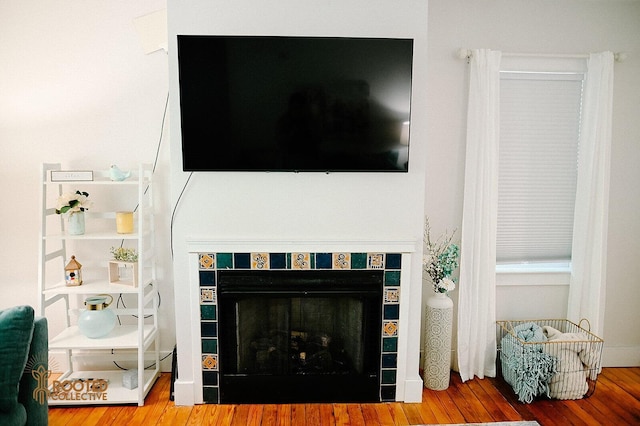 interior details with a tile fireplace and wood finished floors