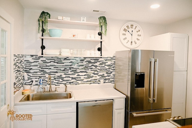 kitchen featuring visible vents, backsplash, appliances with stainless steel finishes, white cabinets, and a sink