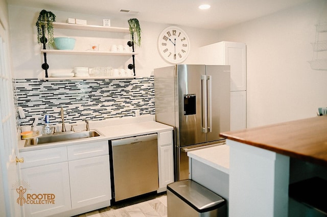 kitchen featuring a sink, tasteful backsplash, white cabinetry, stainless steel appliances, and light countertops