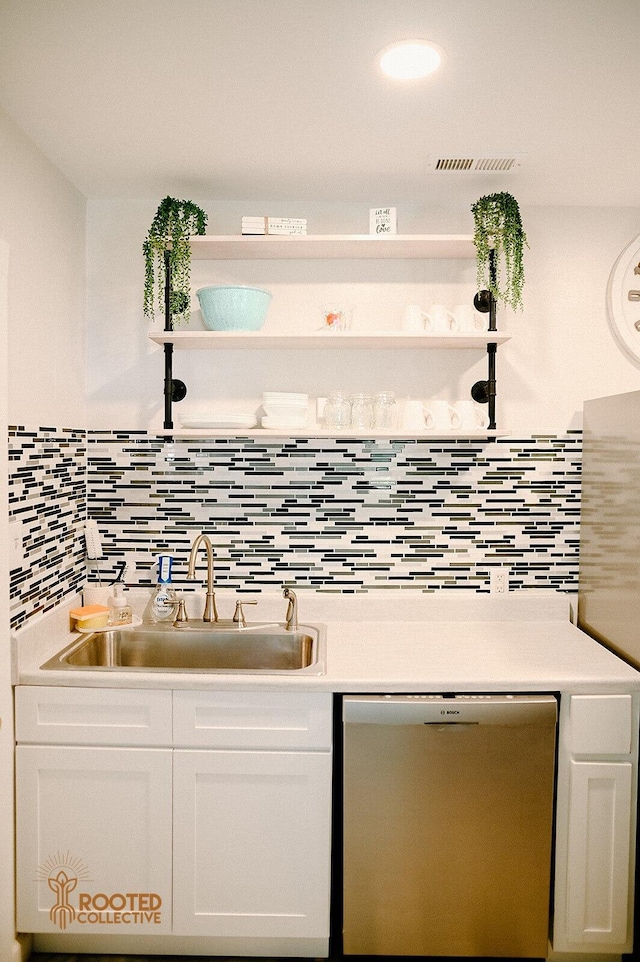 kitchen with a sink, stainless steel dishwasher, light countertops, and white cabinetry