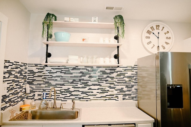 kitchen with tasteful backsplash, visible vents, stainless steel fridge with ice dispenser, light countertops, and a sink