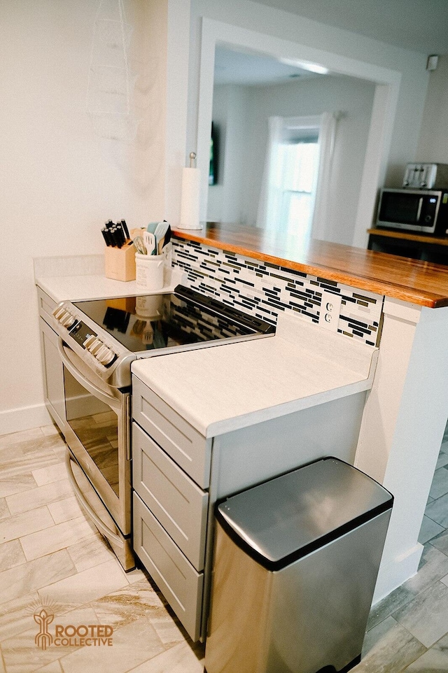 kitchen featuring wood tiled floor, butcher block countertops, gray cabinets, and stainless steel appliances