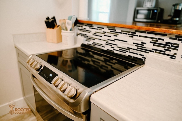 interior details featuring backsplash, light countertops, and electric stove