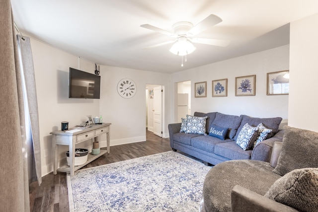 living area featuring baseboards, a ceiling fan, and dark wood-style flooring