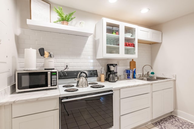 kitchen with range with electric cooktop, a sink, stainless steel microwave, white cabinetry, and glass insert cabinets