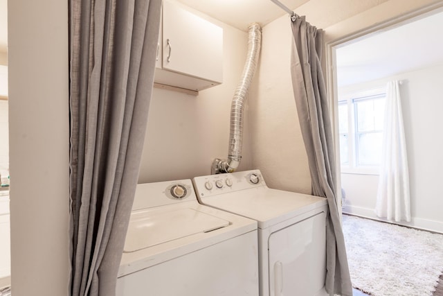 clothes washing area featuring washer and dryer and cabinet space