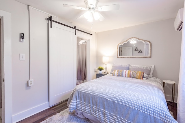 bedroom featuring wood finished floors, baseboards, ceiling fan, an AC wall unit, and a barn door