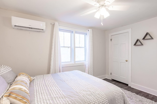 bedroom featuring baseboards, a ceiling fan, an AC wall unit, and dark wood-style flooring