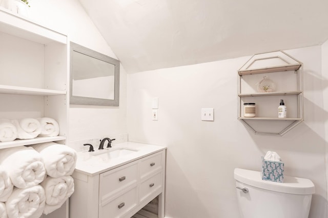 bathroom featuring toilet, vanity, and lofted ceiling