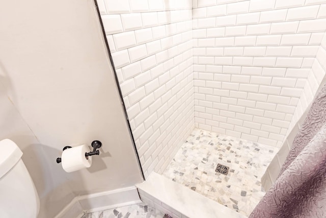 bathroom with baseboards, toilet, marble finish floor, and a stall shower