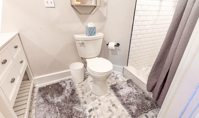 bathroom featuring vanity, toilet, baseboards, and a stall shower