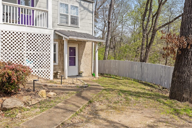 property entrance with stucco siding and fence