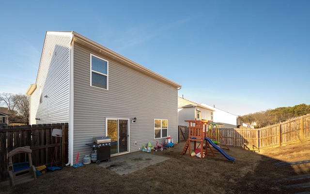 back of property featuring a playground and a patio area