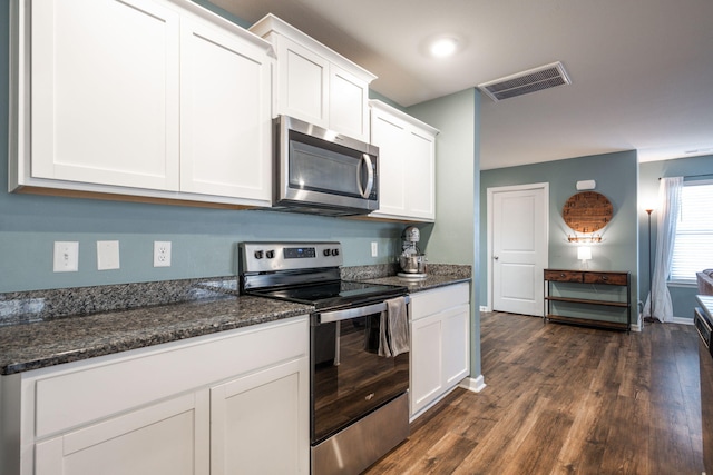 kitchen with dark hardwood / wood-style flooring, dark stone counters, white cabinets, and appliances with stainless steel finishes