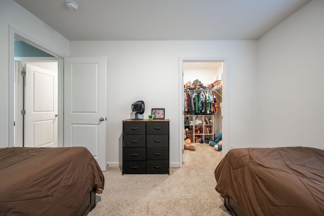 carpeted bedroom featuring a walk in closet and a closet