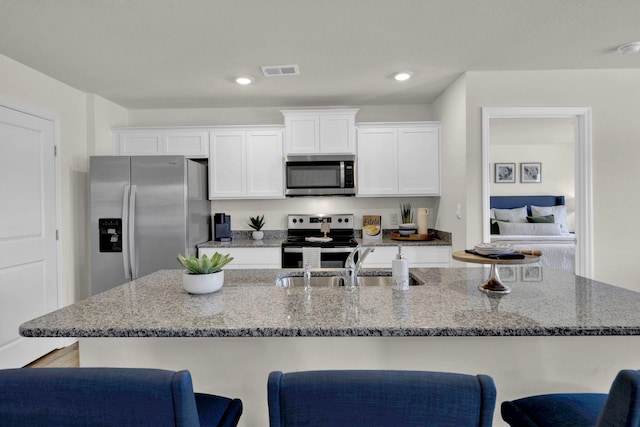 kitchen featuring stone counters, white cabinetry, sink, a kitchen bar, and stainless steel appliances