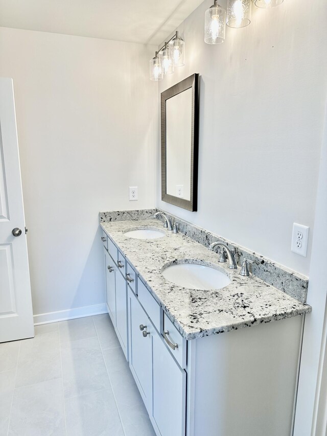 bathroom featuring a sink, baseboards, double vanity, and tile patterned flooring