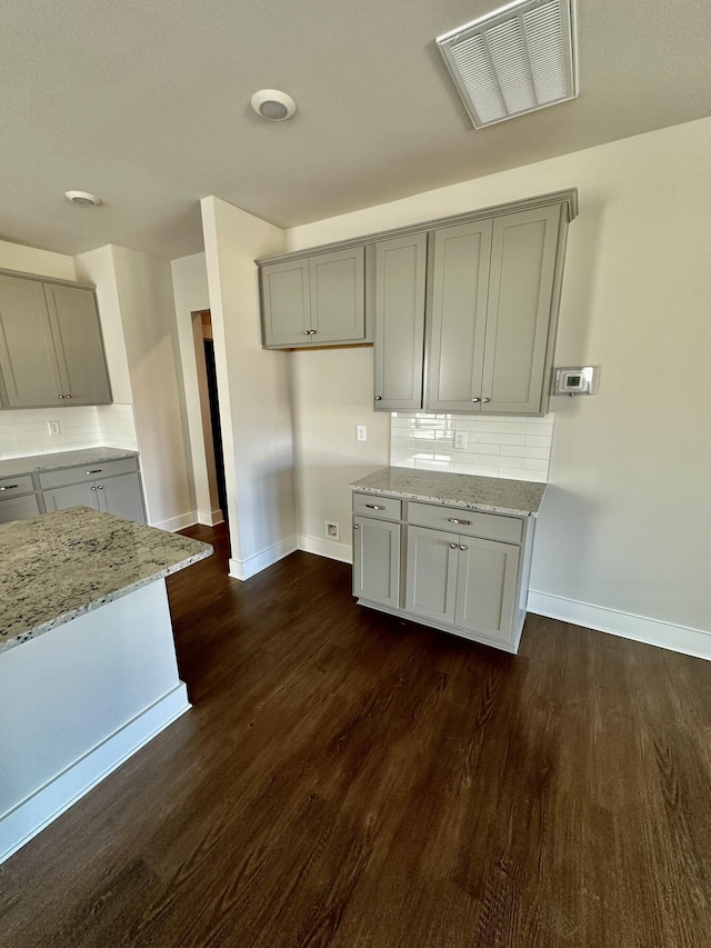 kitchen featuring visible vents, light stone countertops, and gray cabinetry