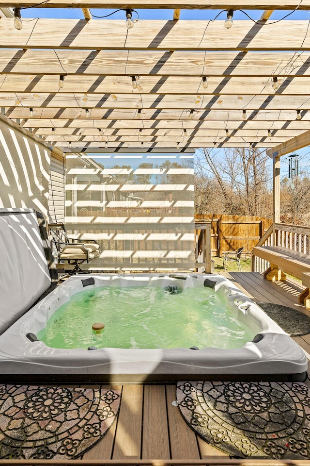 deck with an outdoor hot tub and a pergola