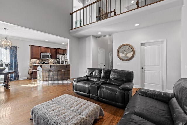 living room with hardwood / wood-style floors, a towering ceiling, and a chandelier