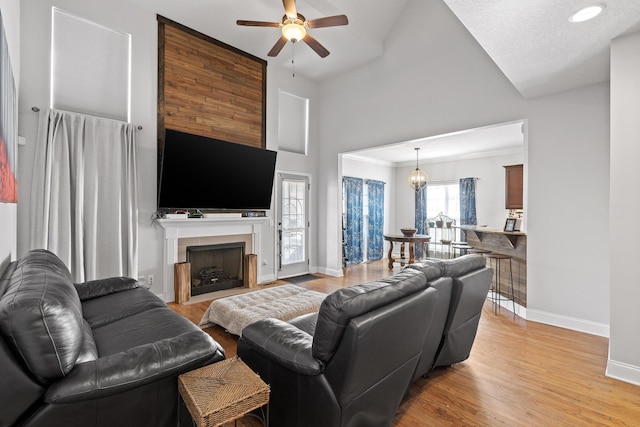 living room featuring ceiling fan with notable chandelier, light hardwood / wood-style flooring, and high vaulted ceiling