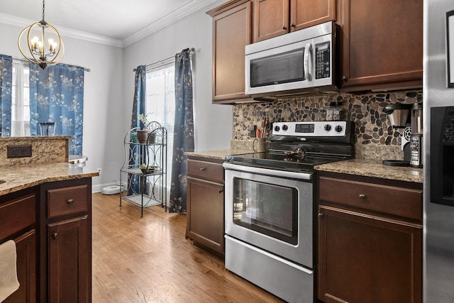 kitchen featuring decorative light fixtures, backsplash, stainless steel appliances, crown molding, and light wood-type flooring