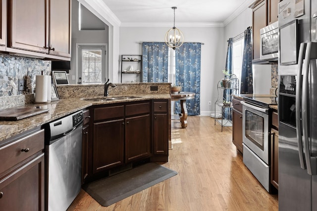 kitchen with sink, crown molding, stone countertops, appliances with stainless steel finishes, and pendant lighting