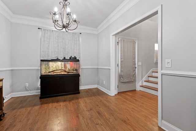 unfurnished dining area featuring crown molding, hardwood / wood-style flooring, and an inviting chandelier