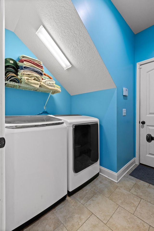 clothes washing area featuring washing machine and dryer, light tile patterned flooring, and a textured ceiling