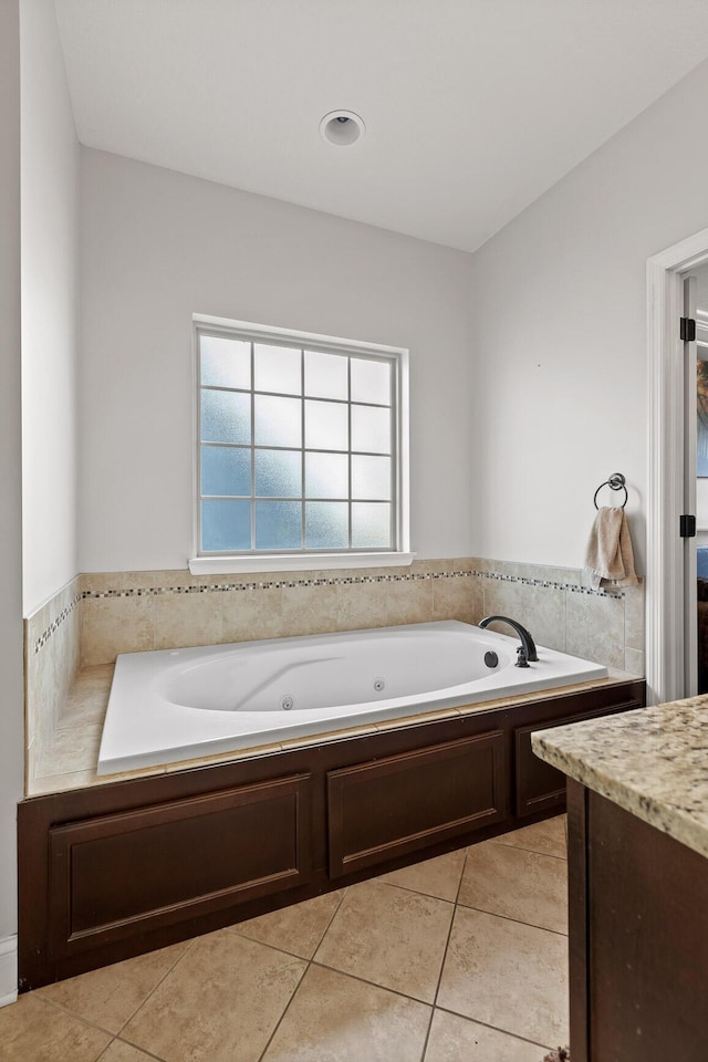 bathroom with a washtub, vanity, and tile patterned flooring