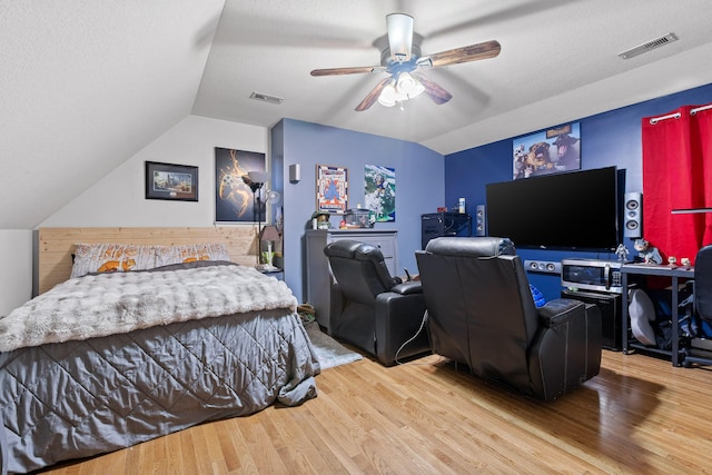 bedroom with hardwood / wood-style flooring, vaulted ceiling, a textured ceiling, and ceiling fan