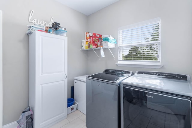 clothes washing area with washing machine and dryer and light tile patterned floors