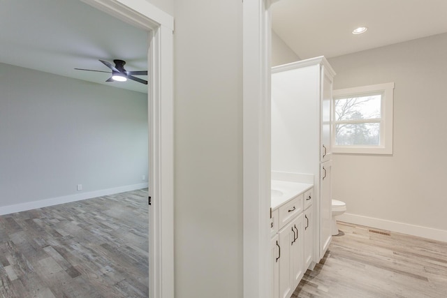 bathroom featuring vanity, ceiling fan, wood-type flooring, and toilet