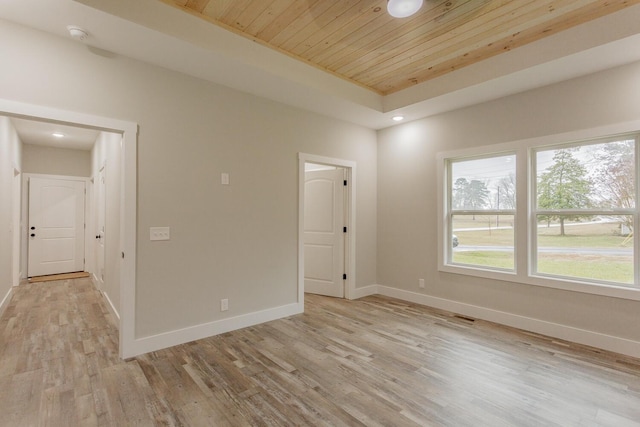 spare room with a raised ceiling, wooden ceiling, and light hardwood / wood-style flooring