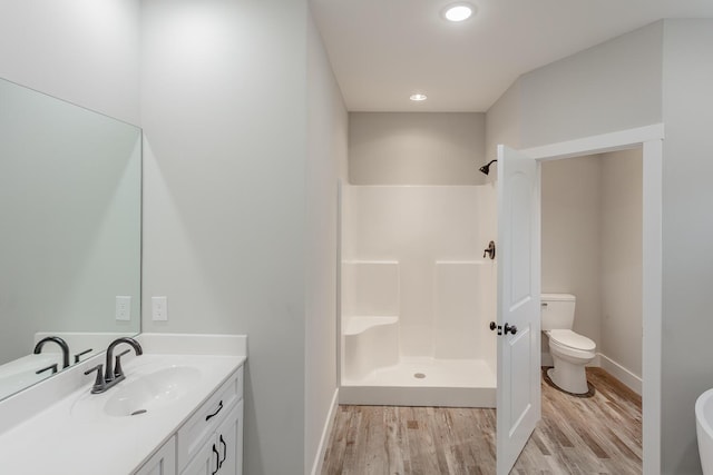 bathroom with hardwood / wood-style flooring, a shower, vanity, and toilet