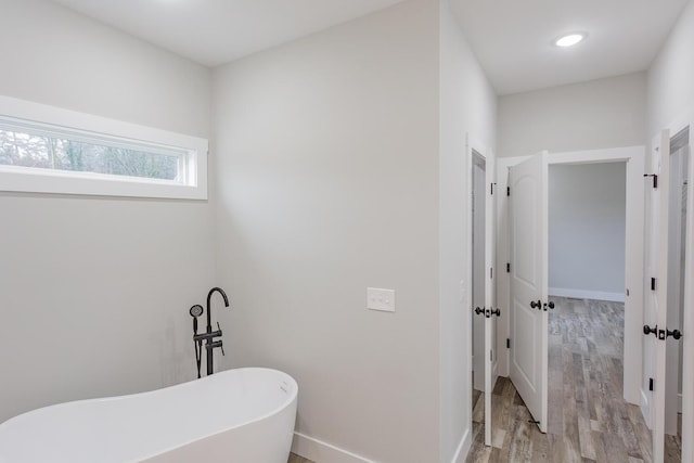 bathroom with hardwood / wood-style flooring and a tub to relax in