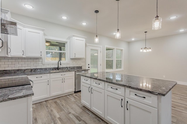 kitchen with light hardwood / wood-style flooring, white cabinetry, a kitchen island, decorative light fixtures, and stainless steel dishwasher