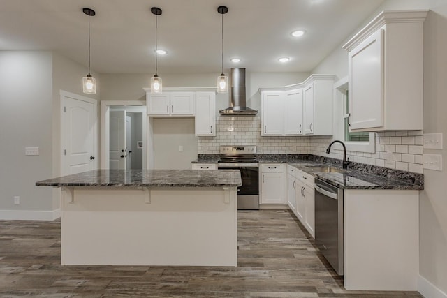 kitchen featuring wall chimney exhaust hood, sink, a kitchen island, stainless steel appliances, and white cabinets