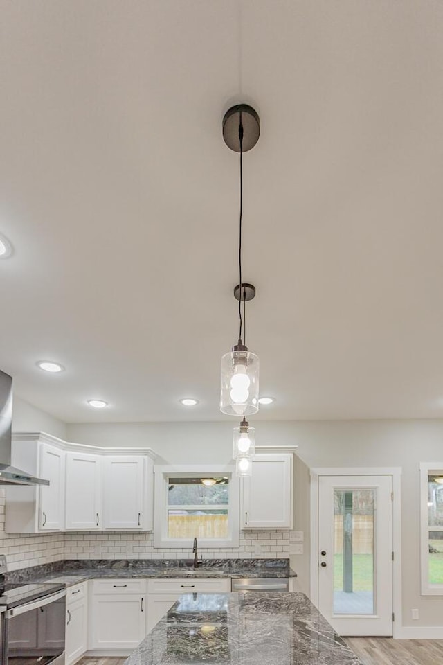 interior space featuring sink, white cabinetry, tasteful backsplash, hanging light fixtures, and stainless steel appliances