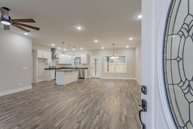 unfurnished living room with ceiling fan, sink, and light hardwood / wood-style floors