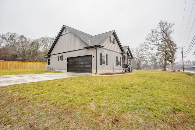 view of side of home with cooling unit, a garage, and a lawn