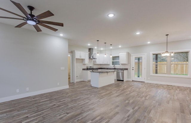 kitchen with white cabinetry, a center island, hanging light fixtures, stainless steel appliances, and wall chimney range hood