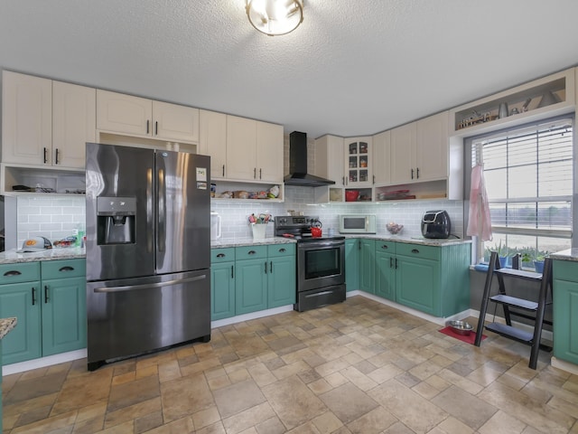 kitchen with stainless steel appliances, wall chimney range hood, white cabinets, and backsplash