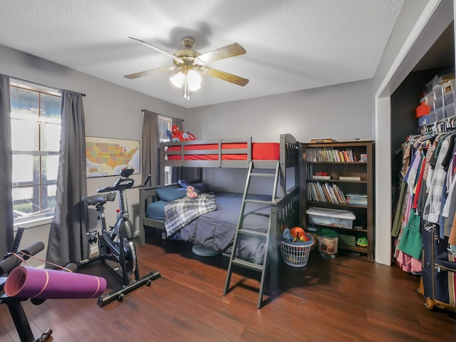 bedroom with dark hardwood / wood-style flooring, ceiling fan, multiple windows, and a textured ceiling