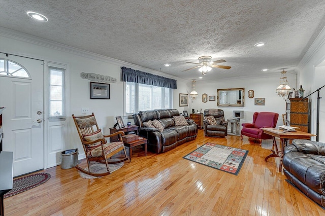 living room featuring ceiling fan, wood-type flooring, ornamental molding, and a textured ceiling