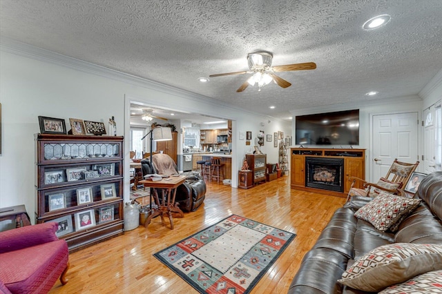 living room featuring crown molding, hardwood / wood-style floors, a textured ceiling, and ceiling fan