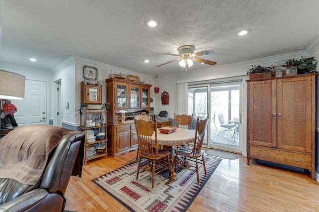 dining space featuring ceiling fan, crown molding, a textured ceiling, and light wood-type flooring