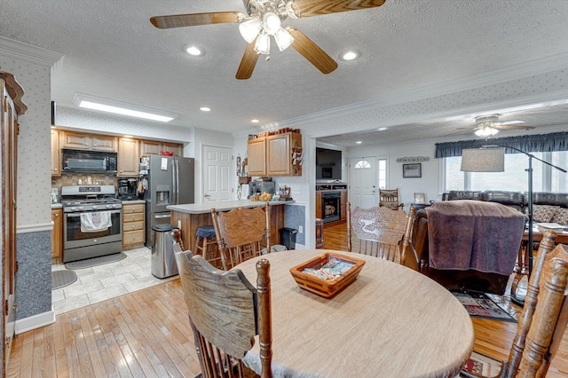 dining space featuring ornamental molding, light wood-type flooring, and a textured ceiling