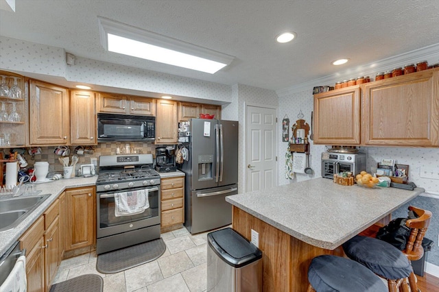 kitchen featuring sink, appliances with stainless steel finishes, a kitchen breakfast bar, a textured ceiling, and a kitchen island